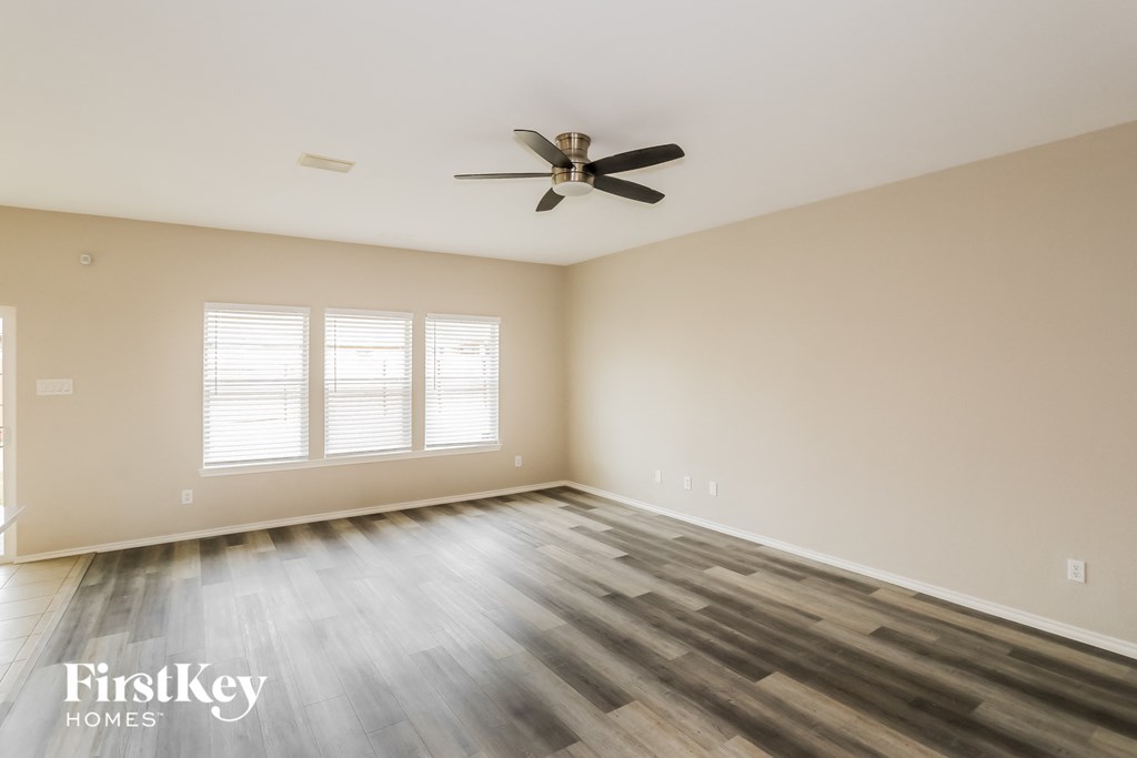 A spacious room with wooden flooring and a ceiling fan.