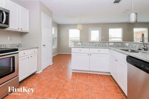 A kitchen with white cabinets and a tiled floor.