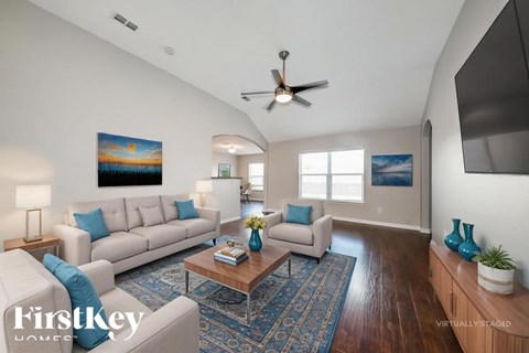 A living room with a white couch and a painting on the wall.