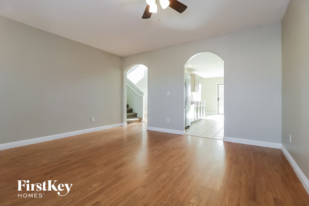 A spacious room with wooden floors and a ceiling fan.