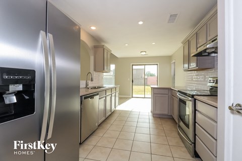 A modern kitchen with a stainless steel refrigerator and tiled flooring.