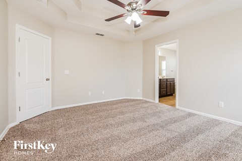 a spacious living room with carpet and a ceiling fan
