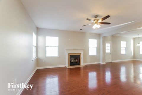 an empty living room with a ceiling fan and a fireplace