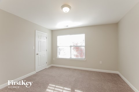 a bedroom with a window and a door and a carpeted floor