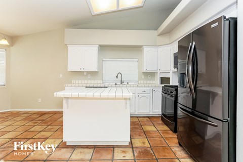 A kitchen with a black refrigerator and white cabinets.