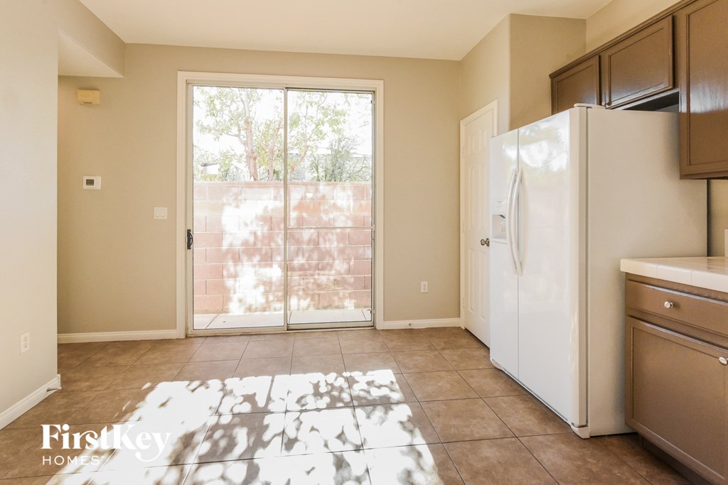A kitchen with a refrigerator, cabinets, and a rug on the floor.