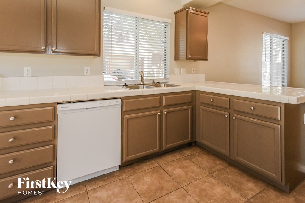 A kitchen with brown cabinets and a white dishwasher.