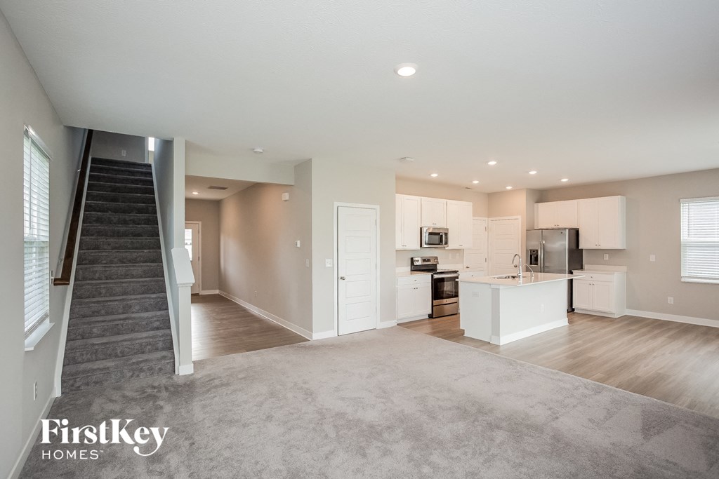 A spacious open floor plan of a modern home with a kitchen, dining area, and living room.