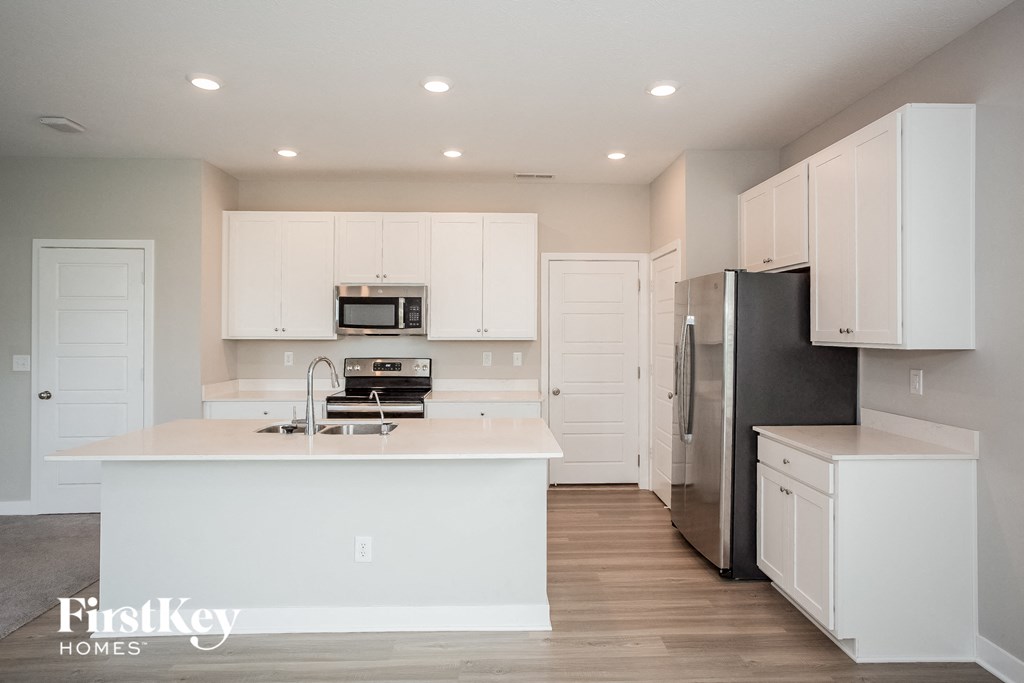 A kitchen with white cabinets and a black refrigerator.
