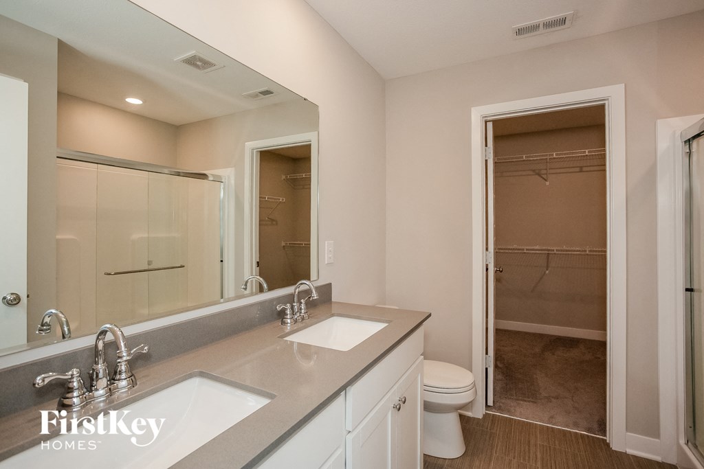 A bathroom with a sink, mirror, toilet and shower.