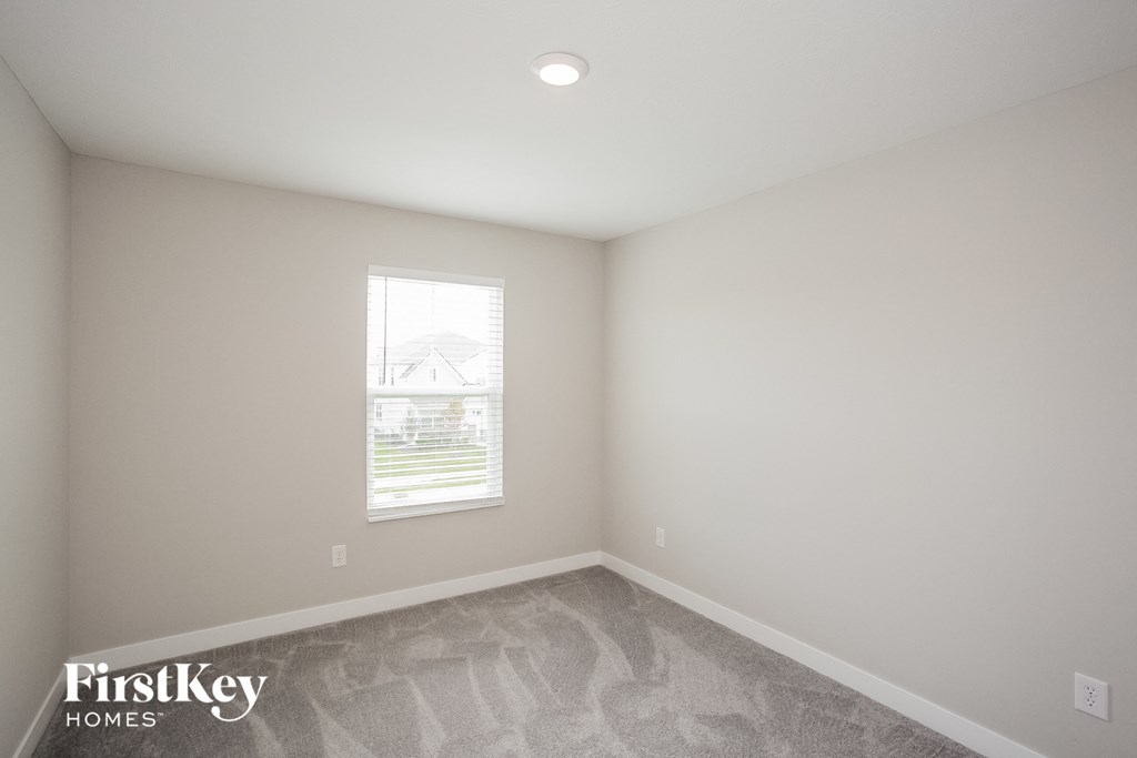 A room with a window and a carpeted floor.