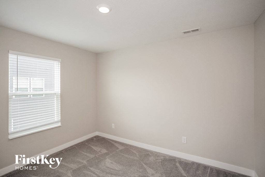 A room with a window and a carpeted floor.