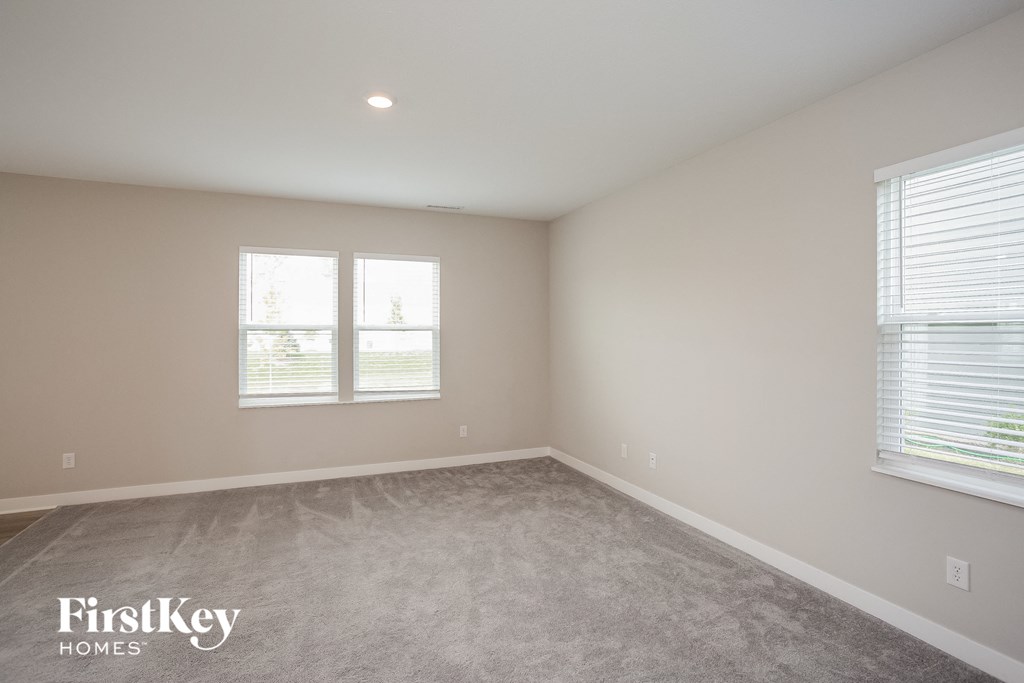 A room with a carpeted floor and a window with blinds.