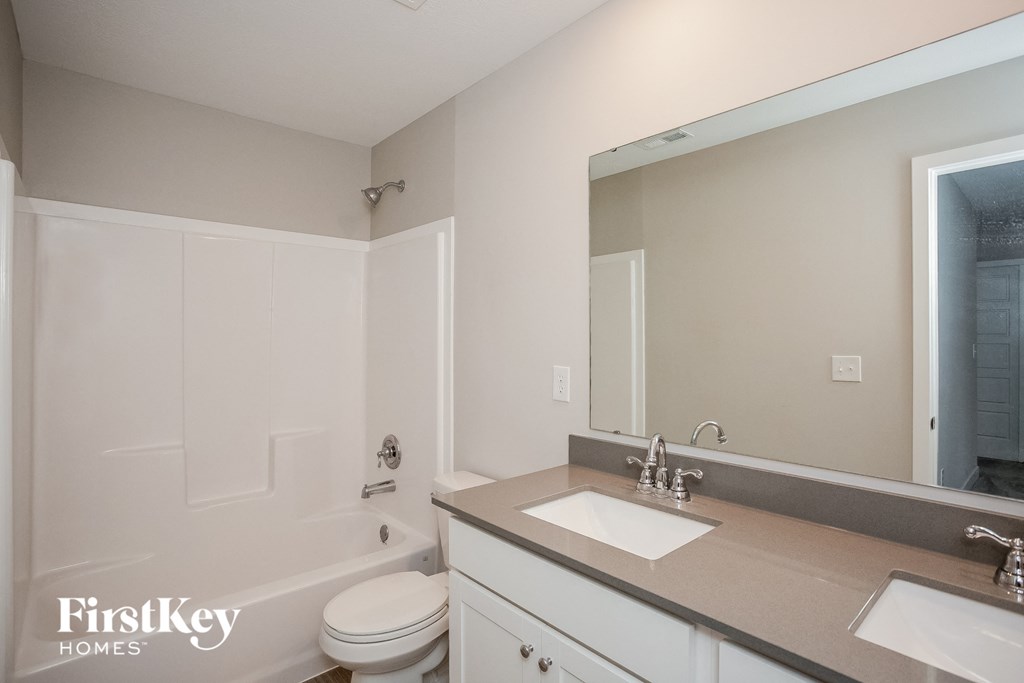A bathroom with a white toilet, sink, and mirror.