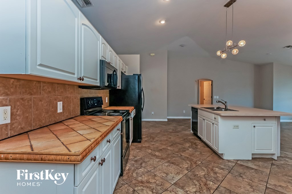 A kitchen with a wooden counter top and a black refrigerator.