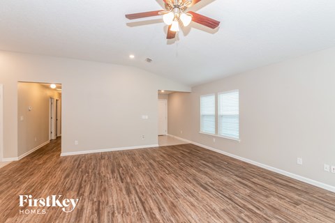 the living room is spacious and has a ceiling fan