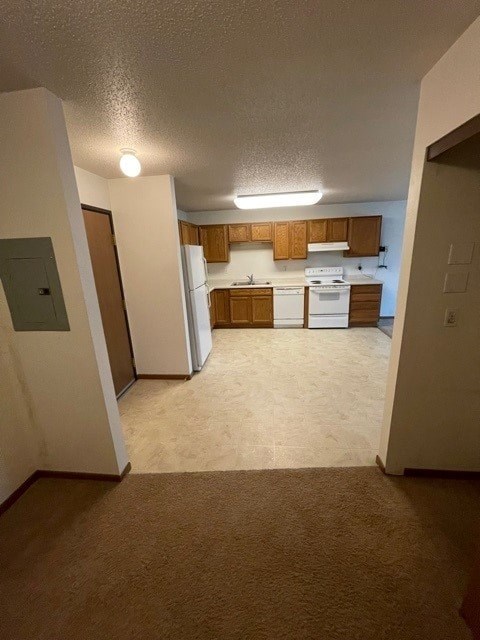 A kitchen with white appliances and wooden cabinets.