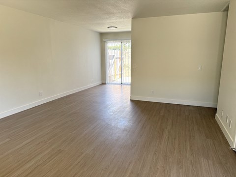 A room with wooden flooring and white walls.