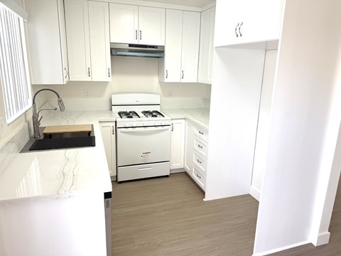 A white kitchen with a stove and a sink.