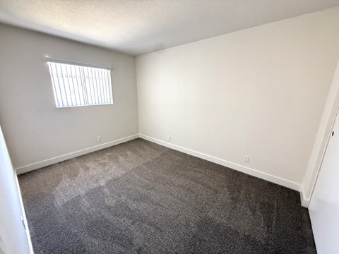 A room with a carpeted floor and a window with blinds.