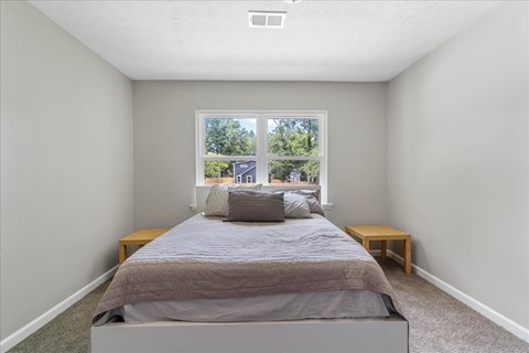 A bedroom with a large bed and a window overlooking a street.
