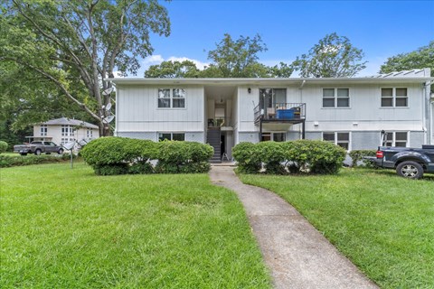 the front of a white house with a walkway and grass