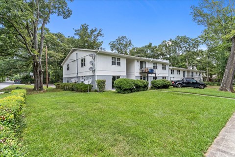 a white house with a lawn and trees in front of it