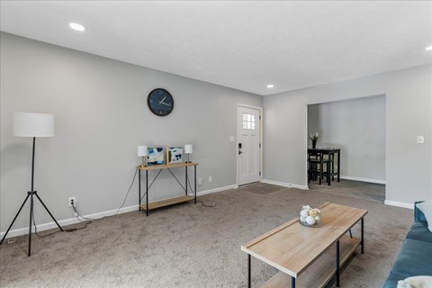 A living room with a wooden table and a clock on the wall.