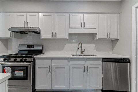 a kitchen with white cabinets and stainless steel appliances