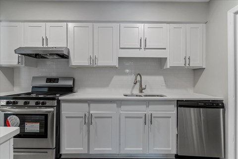 A modern kitchen with white cabinets and stainless steel appliances.