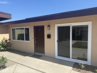 A tan house with a brown door and a glass window.