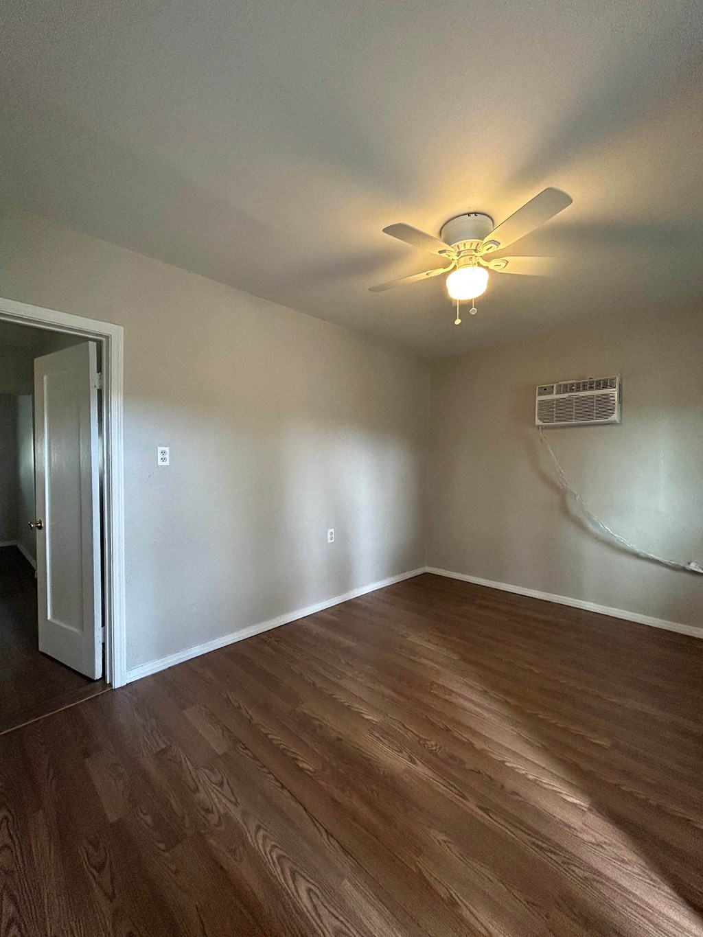 an empty living room with a ceiling fan and wood floors