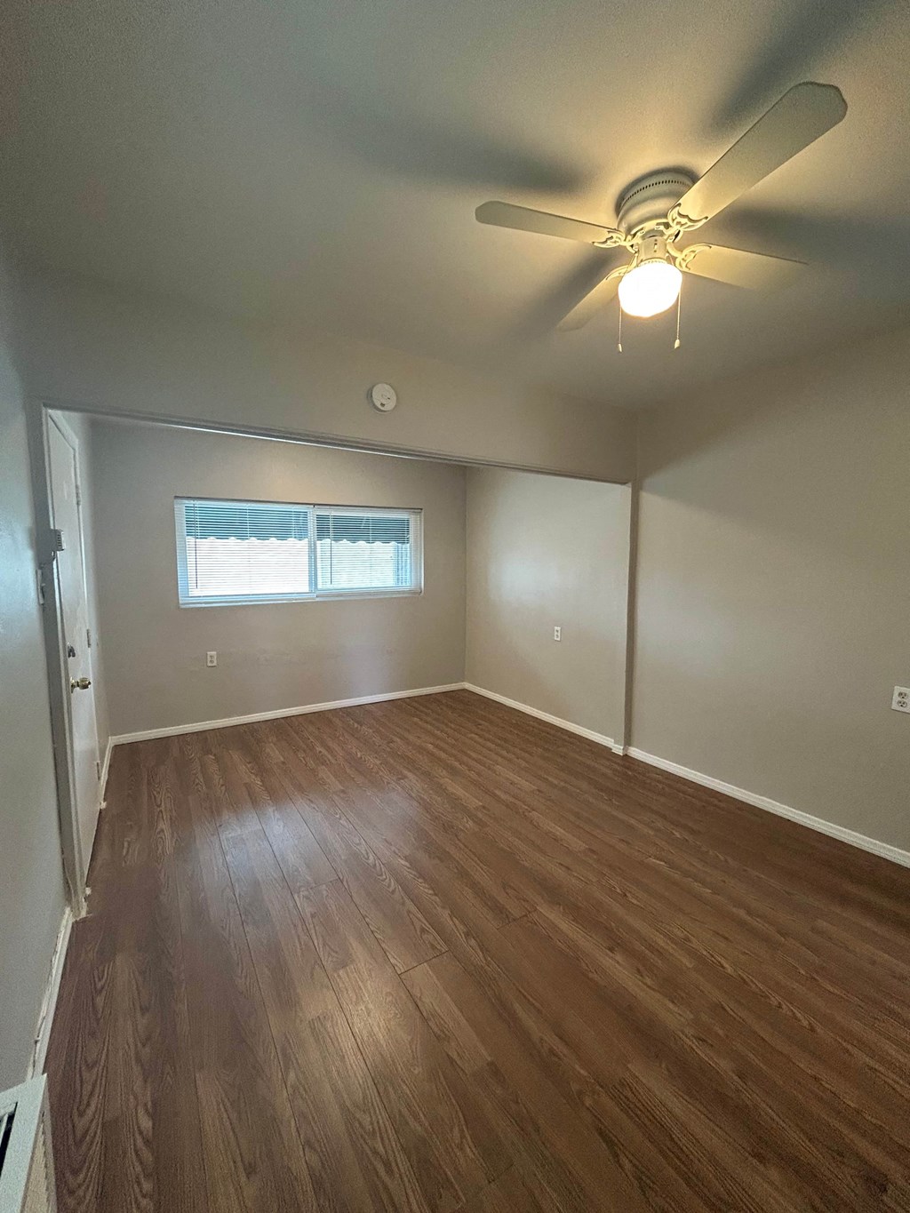 an empty living room with wood floors and a ceiling fan