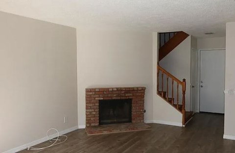 a living room with a brick fireplace and a staircase