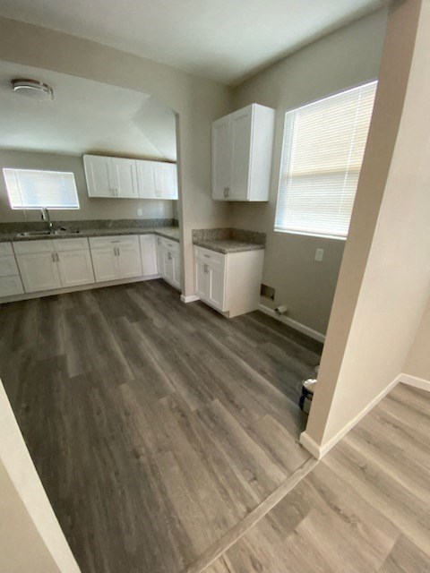 an empty kitchen with wooden floors and white cabinets