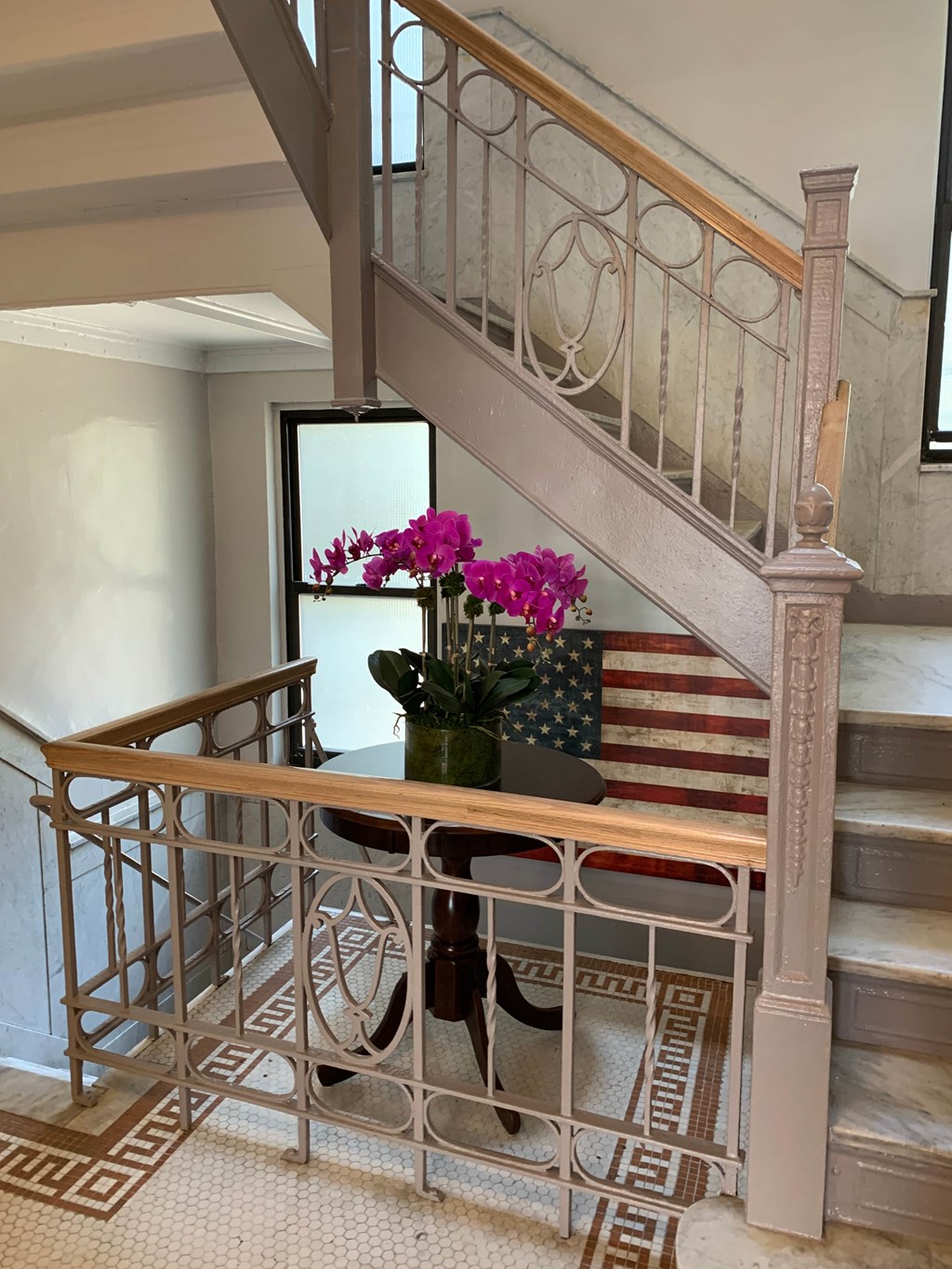 a dining table with pink flowers in front of a staircase