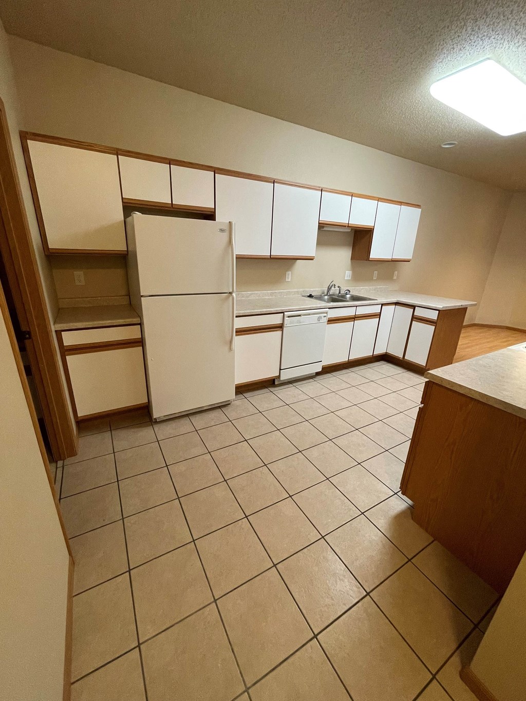 an empty kitchen with white cabinets and appliances and tiled floors