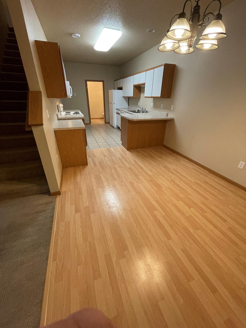 an empty living room with wooden floors and a kitchen