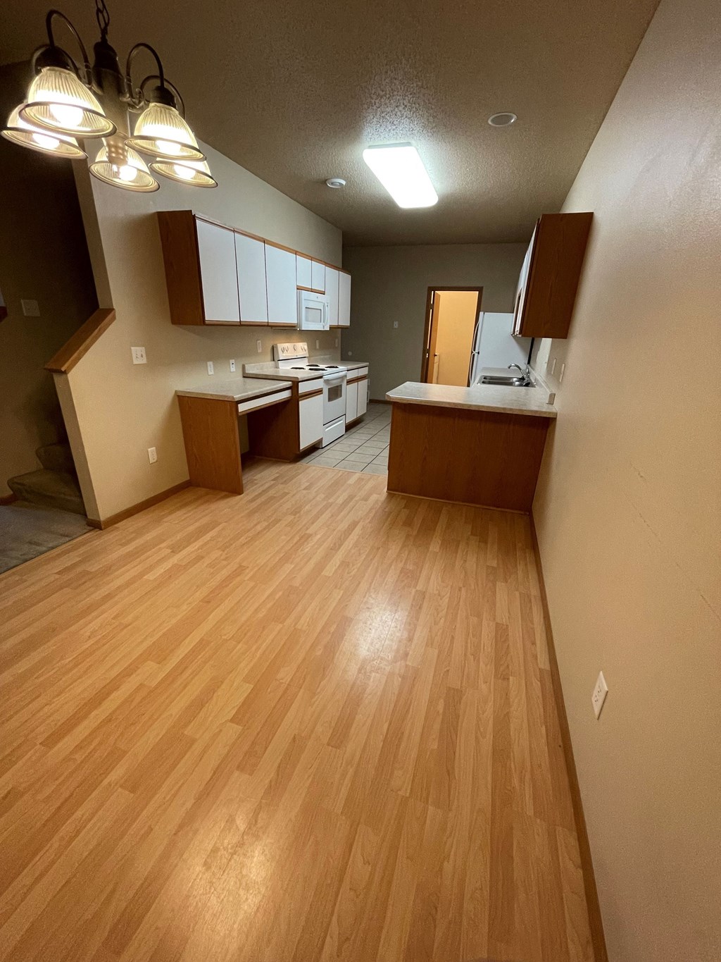 an empty kitchen and living room with wood floors