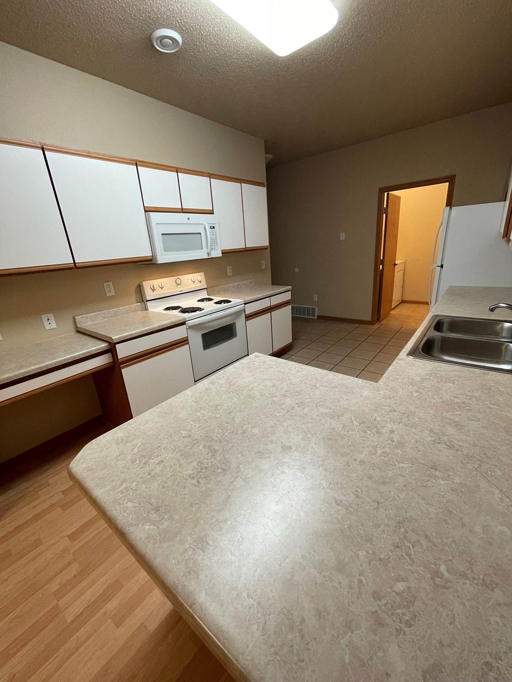 an empty kitchen with white cabinets and stainless steel appliances