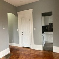 an empty room with a door and a kitchen