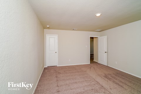 a spacious living room with carpet and a door to a hallway