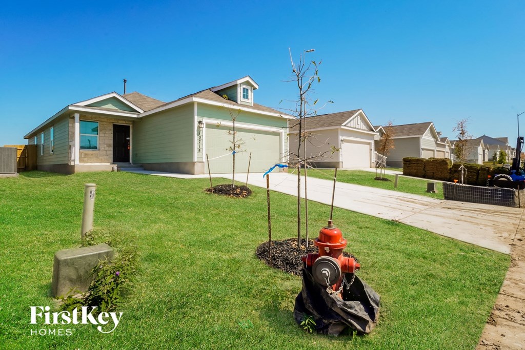 A red fire hydrant is on the grass in front of a house.