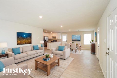 A well-lit, spacious living room with a couch, coffee table, and a painting on the wall.