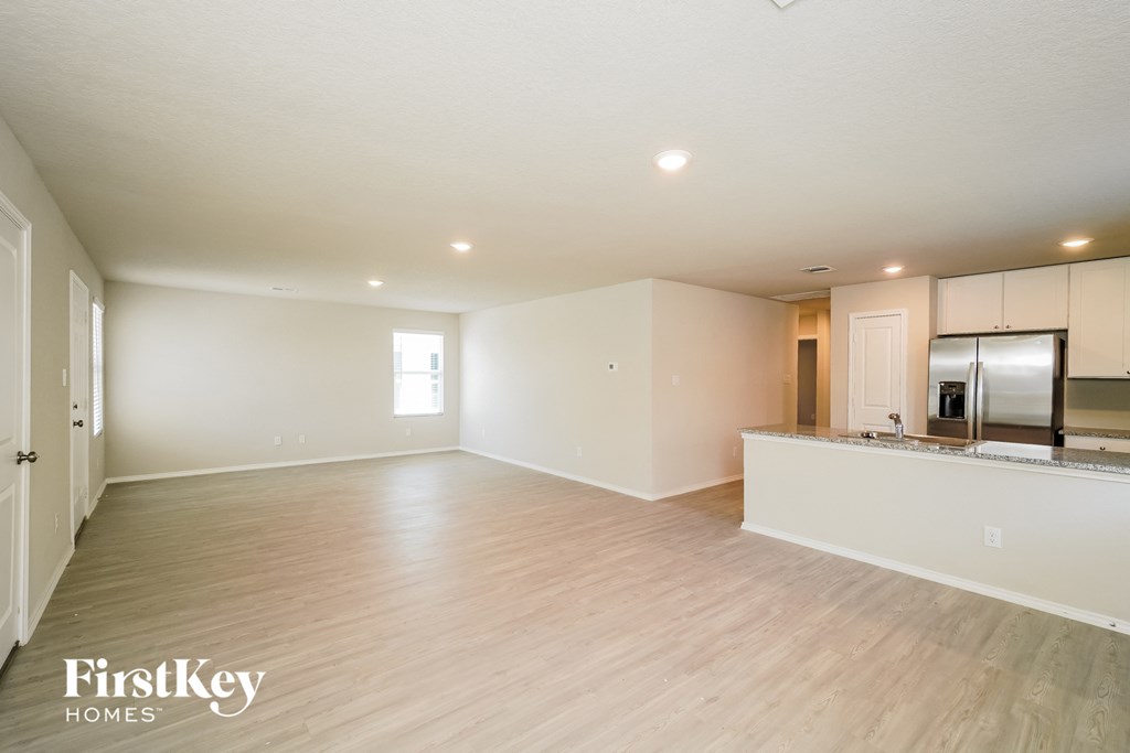 A spacious empty room with wooden flooring and white walls.