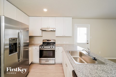 A kitchen with a stainless steel refrigerator and a stainless steel sink.