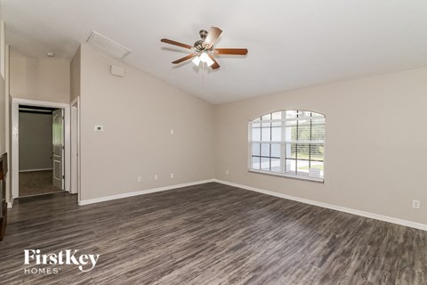 an empty living room with a ceiling fan and a window