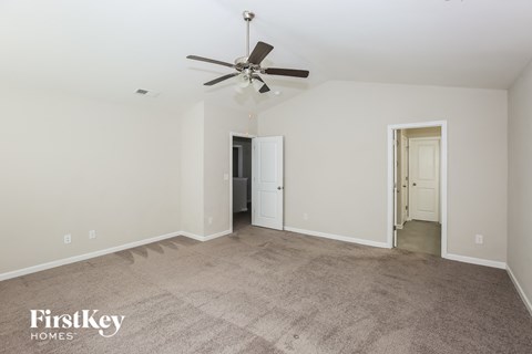 A spacious room with a carpeted floor and a ceiling fan.