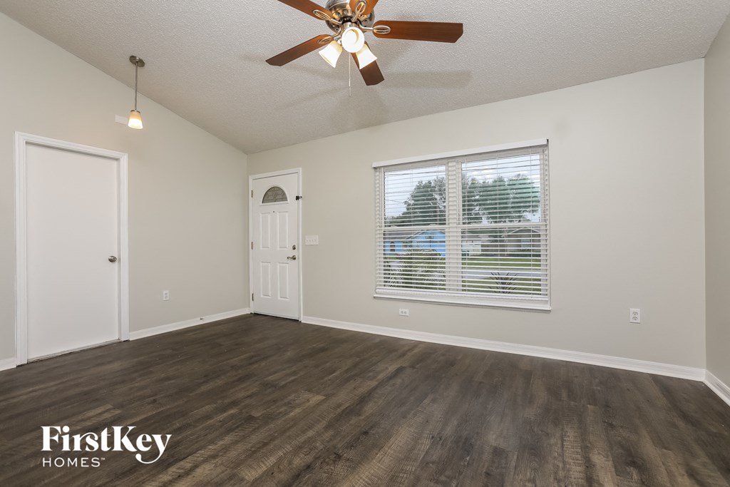 the living room of an empty house with a ceiling fan and a window