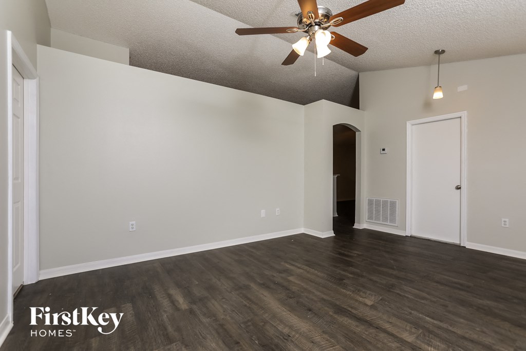 the living room of an empty house with a ceiling fan